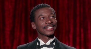 Movie still from “Hollywood Shuffle” (1987), directed by Robert Townsend – A person wearing a suit and bow tie; Close Up shot, Low angle