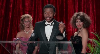 Movie still from “Hollywood Shuffle” (1987), directed by Robert Townsend – A man in a tuxedo holding a wine glass; Medium shot, Low angle