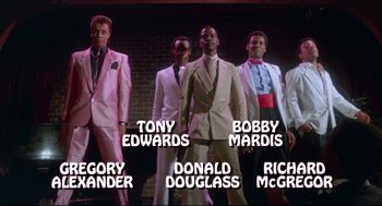 Movie still from “Hollywood Shuffle” (1987), directed by Robert Townsend – A group of men standing next to each other in tuxedos; Wide shot, Low angle