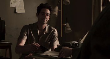 Movie still from “Hollywoodland” (2006), directed by Allen Coulter – A man sitting at a table with papers in front of him; Medium shot, Over the shoulder angle