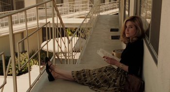 Movie still from “Hollywoodland” (2006), directed by Allen Coulter – A woman sitting on the ground holding a cell phone; Medium shot, High angle