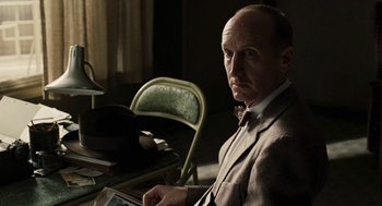Movie still from “Hollywoodland” (2006), directed by Allen Coulter – A man sitting at a desk in a suit and bow tie; Close Up shot, Over the shoulder angle