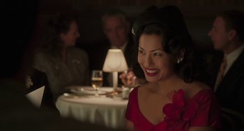 Movie still from “Hollywoodland” (2006), directed by Allen Coulter – A woman in a red dress sitting in front of a table; Close Up shot, Over the shoulder angle