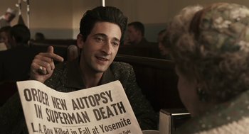 Movie still from “Hollywoodland” (2006), directed by Allen Coulter – A man sitting at a table holding a newspaper; Medium shot, High angle