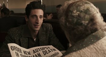 Movie still from “Hollywoodland” (2006), directed by Allen Coulter – A man sitting in front of an older woman holding a newspaper; Close Up shot, Over the shoulder angle