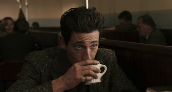 Movie still from “Hollywoodland” (2006), directed by Allen Coulter – A man drinking a cup of coffee while sitting at a table; Close Up shot, Over the shoulder angle