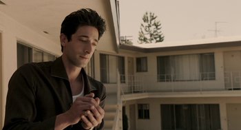 Movie still from “Hollywoodland” (2006), directed by Allen Coulter – A man standing in front of a building with his hands clasped together; Close Up shot, High angle