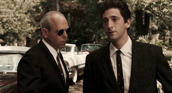 Movie still from “Hollywoodland” (2006), directed by Allen Coulter – A man in a suit and tie standing next to another man in a suit and tie; Medium shot, Over the shoulder angle