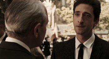 Movie still from “Hollywoodland” (2006), directed by Allen Coulter – A man in a suit and tie standing next to another man; Close Up shot, Over the shoulder angle