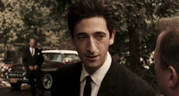 Movie still from “Hollywoodland” (2006), directed by Allen Coulter – A man wearing a suit and tie standing in front of a car; Close Up shot, Over the shoulder angle