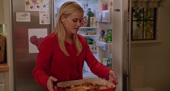 Movie still from “Home Again” (2017), directed by Hallie Meyers-Shyer – A woman in a red shirt is holding a pizza; Medium shot, Over the shoulder angle