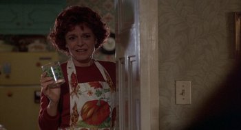 Movie still from “Home for the Holidays” (1995), directed by Jodie Foster – A woman in an apron holding a cell phone in a kitchen; Medium shot, Over the shoulder angle