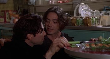 Movie still from “Home for the Holidays” (1995), directed by Jodie Foster – Two men sitting at a table with a plate of food in front of them; Close Up shot, Over the shoulder angle