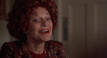 Movie still from “Home for the Holidays” (1995), directed by Jodie Foster – An older woman with red curly hair smiling; Close Up shot, Low angle