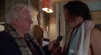 Movie still from “Home for the Holidays” (1995), directed by Jodie Foster – An older man and a younger man looking at a cell phone; Close Up shot, Over the shoulder angle
