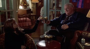 Movie still from “Home for the Holidays” (1995), directed by Jodie Foster – Two people sitting in a living room drinking beer; Medium shot, High angle