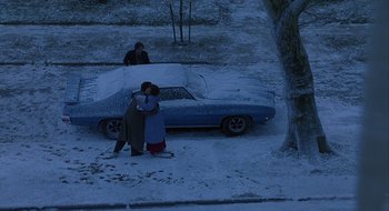 Movie still from “Home for the Holidays” (1995), directed by Jodie Foster – Two people hug in front of a car in the snow; Wide shot, Overhead angle