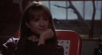 Movie still from “Home for the Holidays” (1995), directed by Jodie Foster – A woman sitting on a red chair with her chin resting on her hand; Close Up shot, Over the shoulder angle