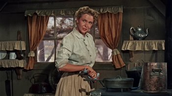 Movie still from “Hondo” (1953), directed by John Farrow – A woman standing in front of an open window; Medium shot, Low angle