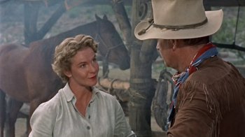 Movie still from “Hondo” (1953), directed by John Farrow – A man and a woman talking to each other in front of horses; Medium shot, Over the shoulder angle