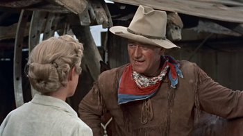 Movie still from “Hondo” (1953), directed by John Farrow – A man and a woman talking in a cowboy outfit; Medium shot, Over the shoulder angle