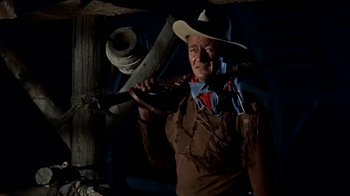 Movie still from “Hondo” (1953), directed by John Farrow – A man in a cowboy hat holding a rifle; Medium shot, Low angle