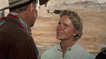 Movie still from “Hondo” (1953), directed by John Farrow – An older man and a younger woman are talking to each other; Close Up shot, Over the shoulder angle