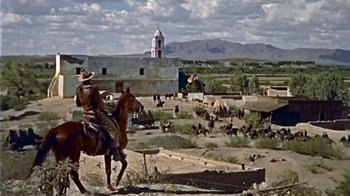 Movie still from “Hondo” (1953), directed by John Farrow – A man riding a horse in the middle of the desert; Extreme Wide shot, Low angle