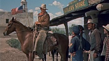 Movie still from “Hondo” (1953), directed by John Farrow – A man riding on the back of a brown horse; Wide shot, Low angle