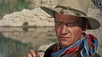 Movie still from “Hondo” (1953), directed by John Farrow – A man in a cowboy hat holding a bug; Close Up shot, Over the shoulder angle