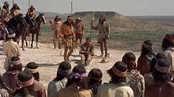 Movie still from “Hondo” (1953), directed by John Farrow – A group of people dressed as native americans in front of a crowd; Wide shot, Over the shoulder angle