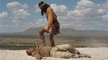 Movie still from “Hondo” (1953), directed by John Farrow – A man laying on the ground next to a woman; Wide shot, Low angle