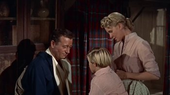 Movie still from “Hondo” (1953), directed by John Farrow – A man and two women standing next to each other in a room; Medium shot, Low angle