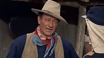 Movie still from “Hondo” (1953), directed by John Farrow – A man wearing a cowboy hat and a vest; Close Up shot, Over the shoulder angle
