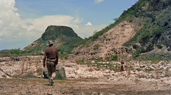 Movie still from “Hondo” (1953), directed by John Farrow – A man and a woman walking on a dirt road; Extreme Wide shot, Low angle