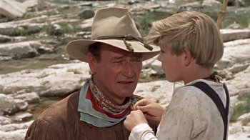 Movie still from “Hondo” (1953), directed by John Farrow – A man in a cowboy hat and a young boy in a cowboy outfit; Close Up shot, Over the shoulder angle