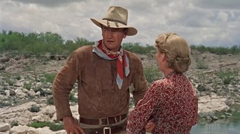 Movie still from “Hondo” (1953), directed by John Farrow – A man and a woman talking in the desert; Medium shot, Over the shoulder angle
