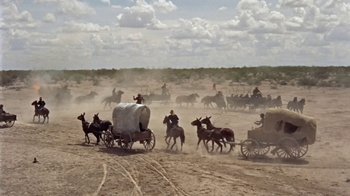 Movie still from “Hondo” (1953), directed by John Farrow – A group of people riding horses on a dirt field; Extreme Wide shot, High angle