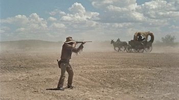 Movie still from “Hondo” (1953), directed by John Farrow – A man with a gun in the middle of the desert; Wide shot, Low angle