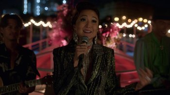 Movie still from “Emily in Paris” (2020), created by Darren Star – A woman is holding a microphone in her hand; Medium shot, Over the shoulder angle
