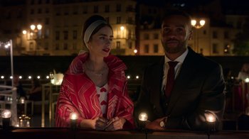 Movie still from “Emily in Paris” (2020), created by Darren Star – A man and a woman sitting next to each other; Medium shot, Over the shoulder angle