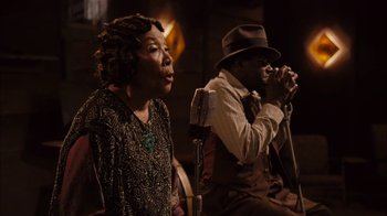 Movie still from “Honeydripper” (2007), directed by John Sayles – A man and a woman singing into microphones; Medium shot, High angle
