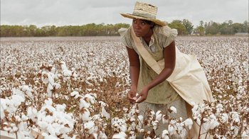 Movie still from “Honeydripper” (2007), directed by John Sayles – A woman in a straw hat picking cotton in a field; Medium shot, High angle