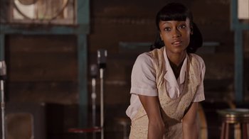 Movie still from “Honeydripper” (2007), directed by John Sayles – A woman in a white shirt and a yellow apron; Medium shot, Over the shoulder angle