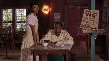 Movie still from “Honeydripper” (2007), directed by John Sayles – A man and a woman sitting at a dinner table; Medium shot, Low angle