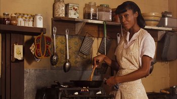Movie still from “Honeydripper” (2007), directed by John Sayles – A woman standing in front of a stove cooking food; Medium shot, High angle
