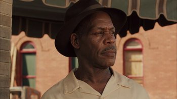 Movie still from “Honeydripper” (2007), directed by John Sayles – An older man wearing a brown hat and a white shirt; Close Up shot, Low angle