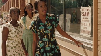 Movie still from “Honeydripper” (2007), directed by John Sayles – Two young women walking down the sidewalk in front of a building; Medium shot, Over the shoulder angle
