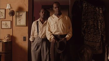 Movie still from “Honeydripper” (2007), directed by John Sayles – A couple of men standing next to each other in a room; Medium shot, Low angle