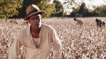 Movie still from “Honeydripper” (2007), directed by John Sayles – A man wearing a hat standing in the middle of a cotton field; Medium shot, Over the shoulder angle